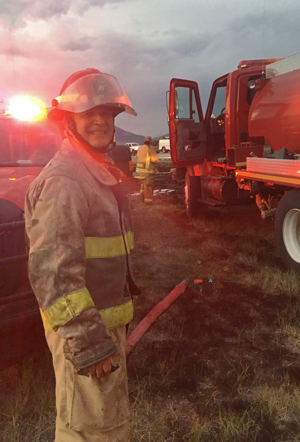 smiling-fireman-firetruck-axe-grassland.jpg
